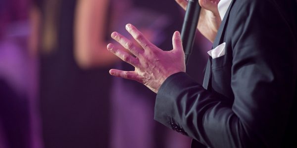 A person in a suit using a microphone at an event.