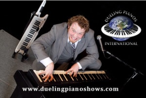 Man playing piano with a smile, next to duelingpianoshow.com logo.