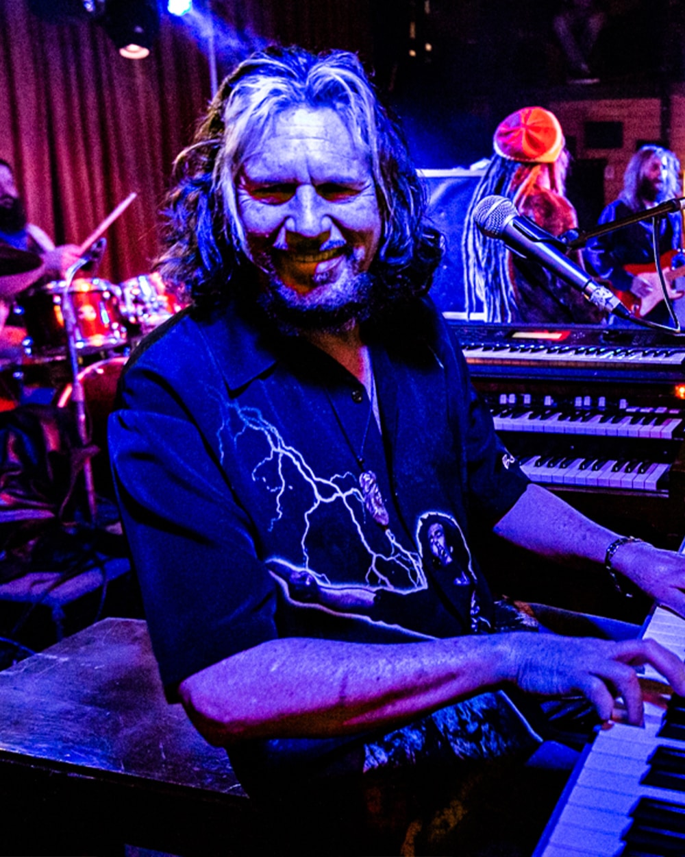 A person playing a keyboard on stage with colorful lights.