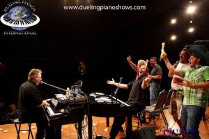 People enjoying a lively dueling piano performance on stage.